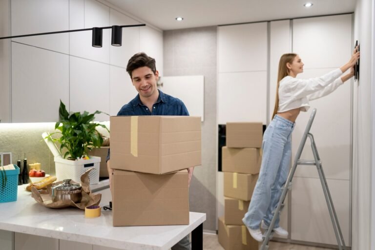 woman-hanging-frame-wall-while-her-boyfriend-is-handling-boxes_23-2149312723